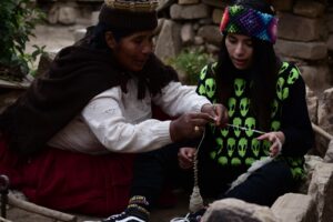 Una comunaria enseña a una joven turista el arte de hilar. Foto: Álvaro Valero.